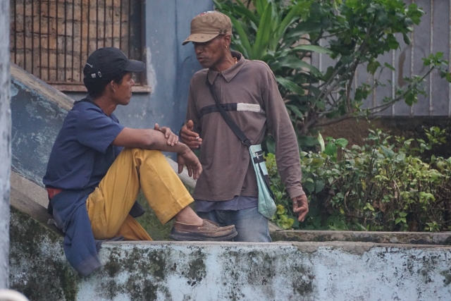 Two Cuban men speaking to one another in the street.